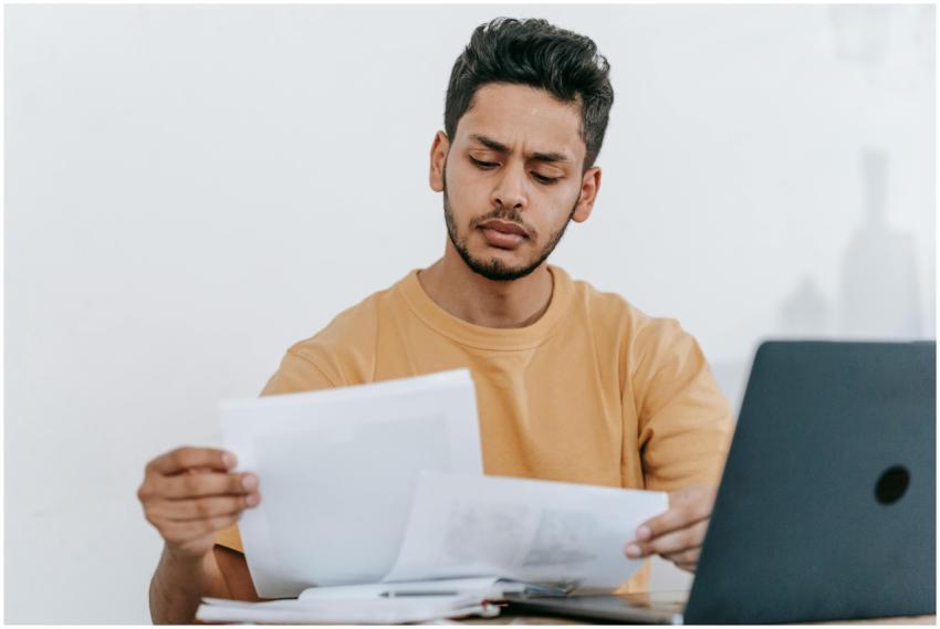 Focused young man reviewing paperwork at his desk,