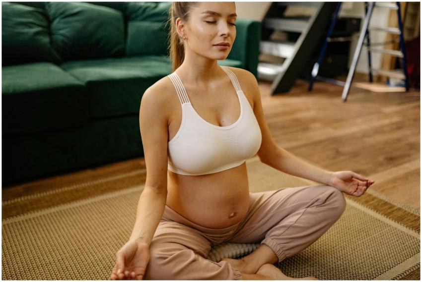 Pregnant woman meditating in half lotus position a