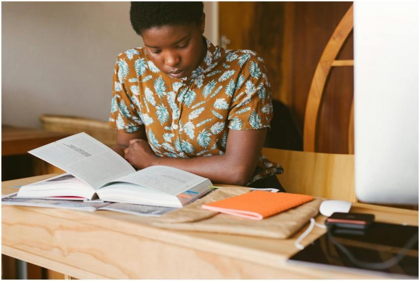 A young woman studies a book at her desk in a warm