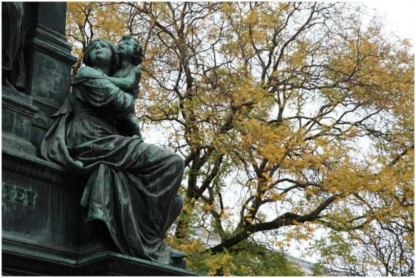 A bronze statue set against vibrant autumn leaves