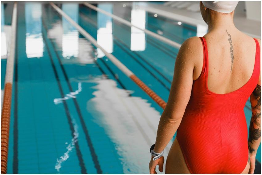 A female swimmer in a red swimsuit prepares for a