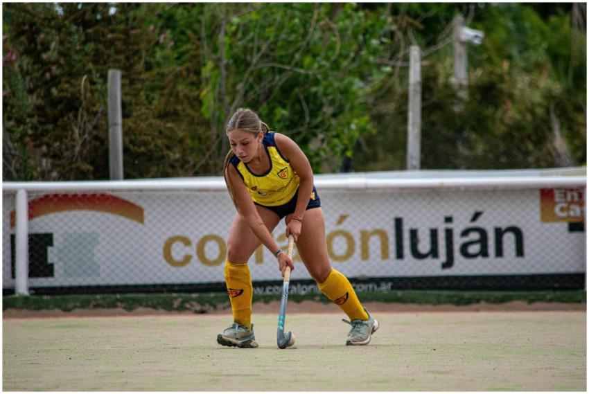 A young female athlete playing field hockey outdoo
