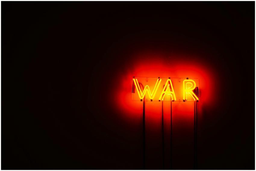 Bright neon WAR sign illuminating a dark space, co