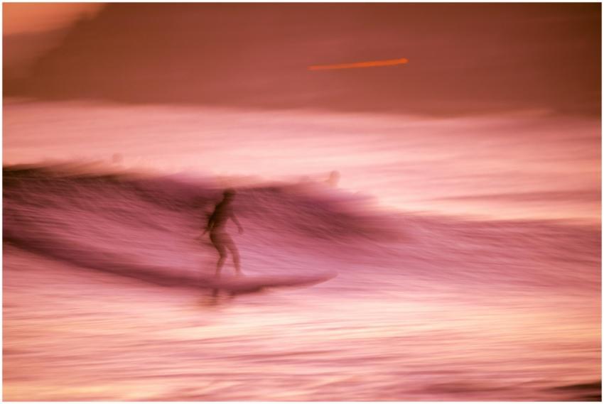 Artistic shot of a surfer riding waves at sunset i