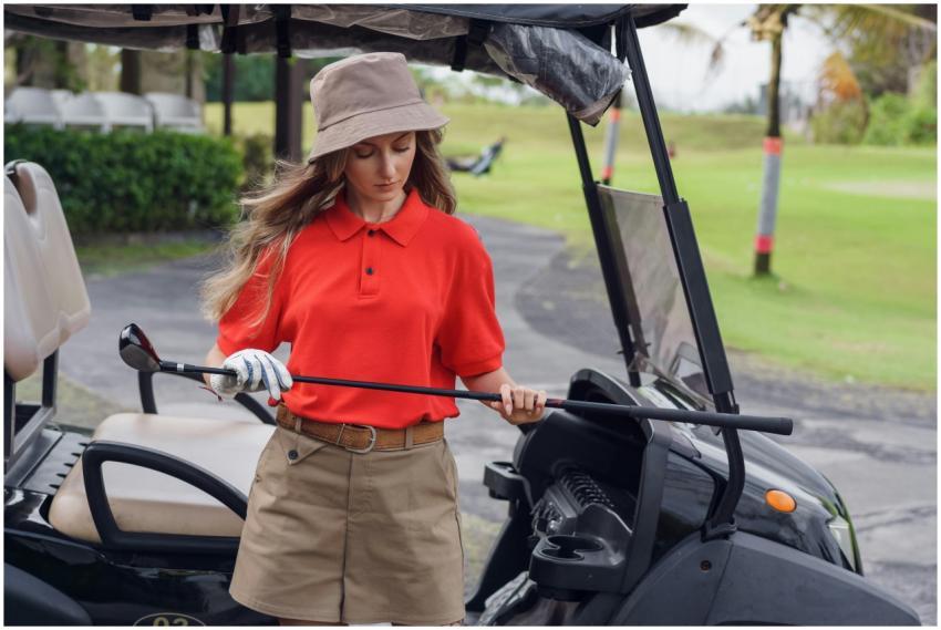 Woman in red and khaki golfing outfit standing by