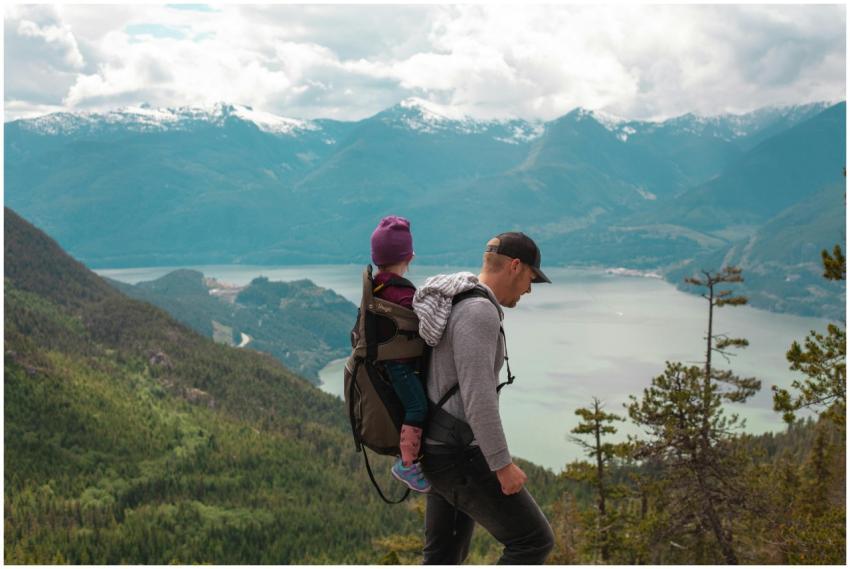 A father carries his child on a scenic mountain tr