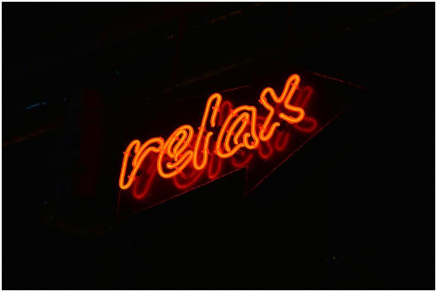A glowing red neon 'relax' sign against a black ba