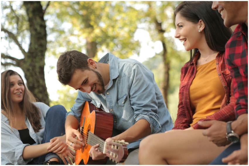 Young friends having fun playing guitar and laughi
