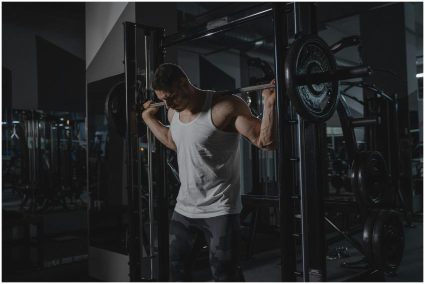 Athletic man in activewear lifting weights at the