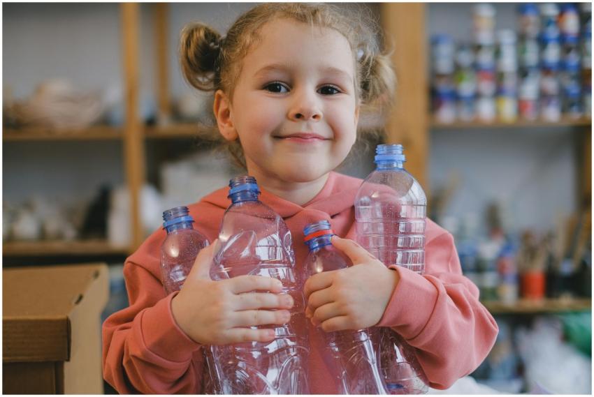 Happy child holding plastic bottles, smiling indoo