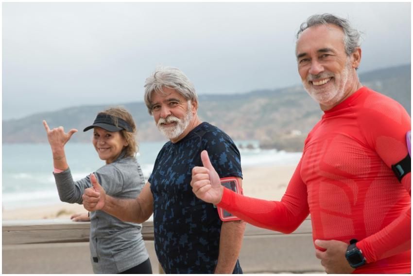 Smiling senior friends exercising on a beach in Po