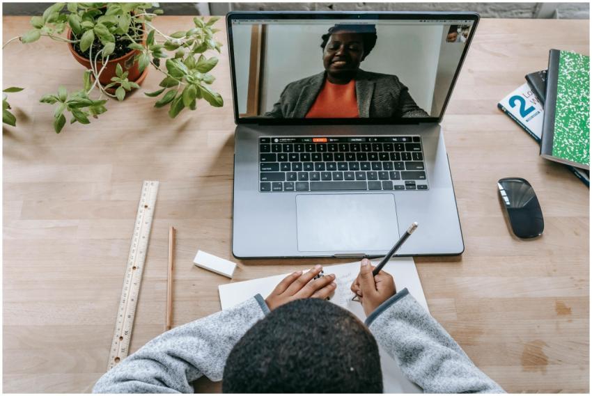 A student takes notes during an online class with