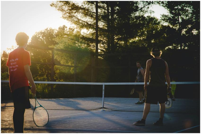 Three young men playing tennis on an outdoor court