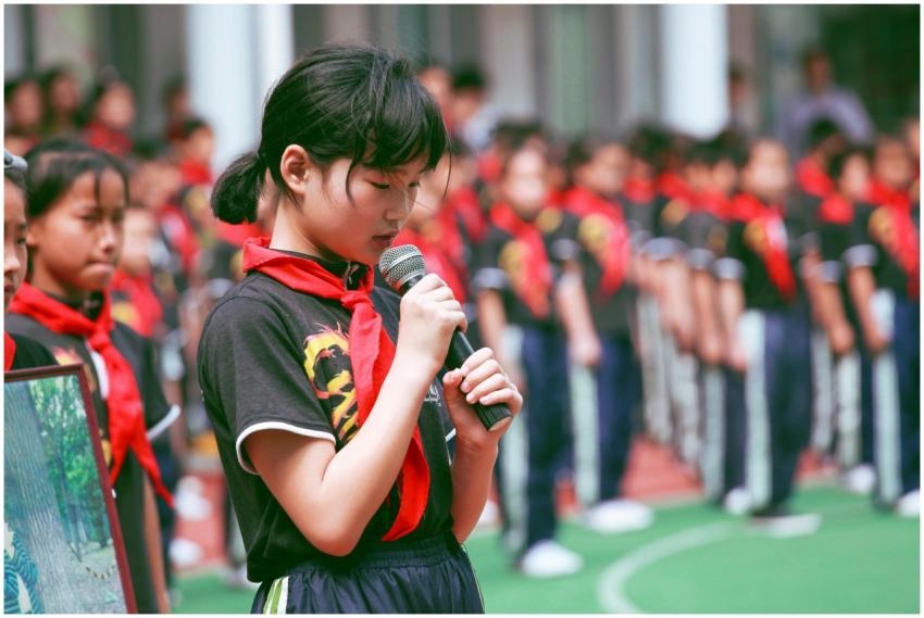 A young girl in uniform with a red scarf speaks in