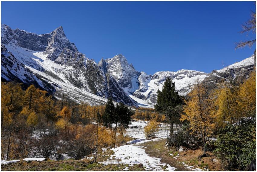 Stunning snowy mountains with autumn trees and a c