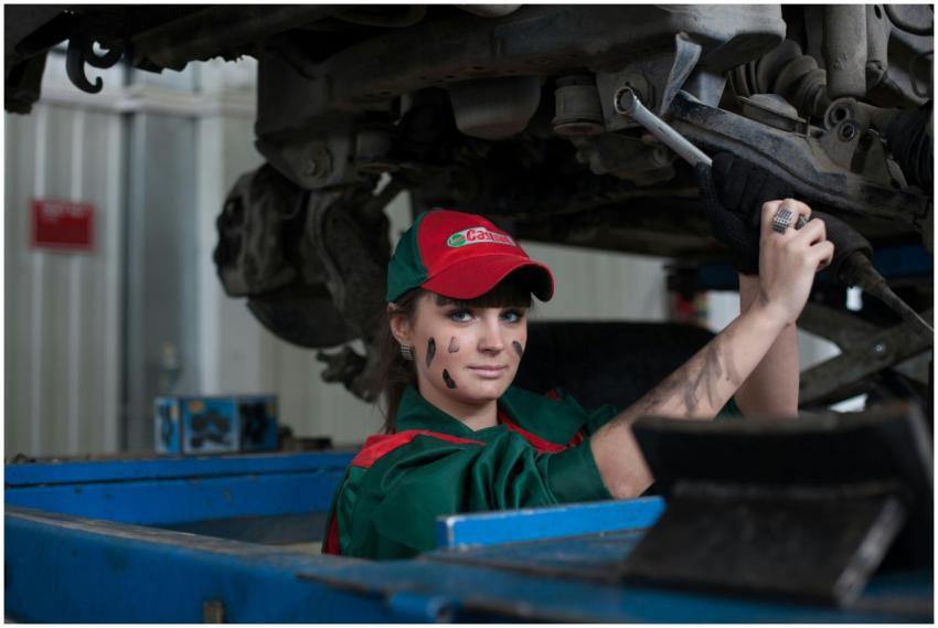 Female mechanic maintaining a car in an auto repai