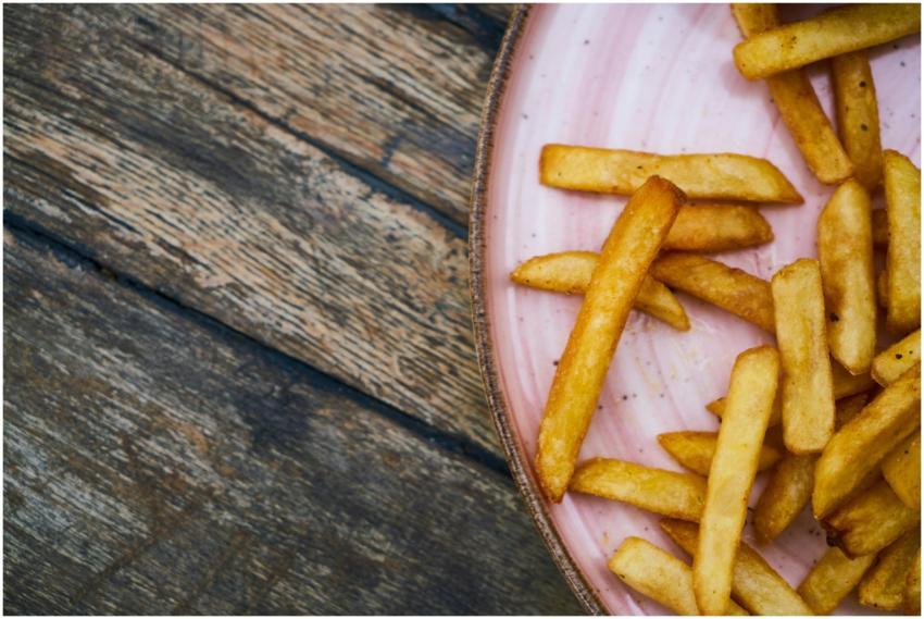 Close-up of golden french fries on a pink plate ov