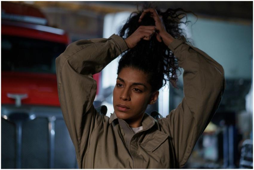 Woman in beige uniform tying her hair in front of