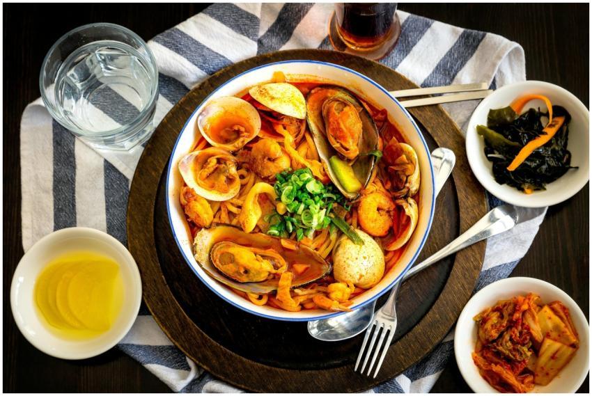 A vibrant Korean seafood noodle dish with side dis