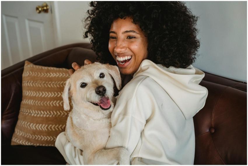 Happy young black lady hugging with dog while sitt