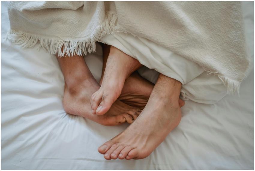 Intimate close-up of two men's feet intertwined un