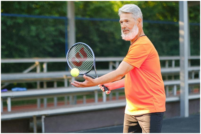 Side view of cheerful senior sportsman standing wi