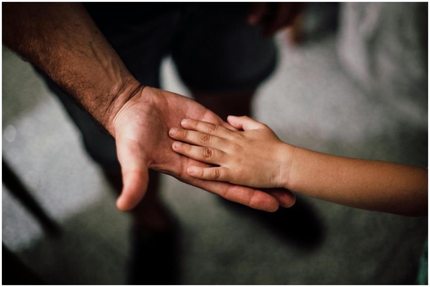 Close-up of a child's hand resting gently on a man