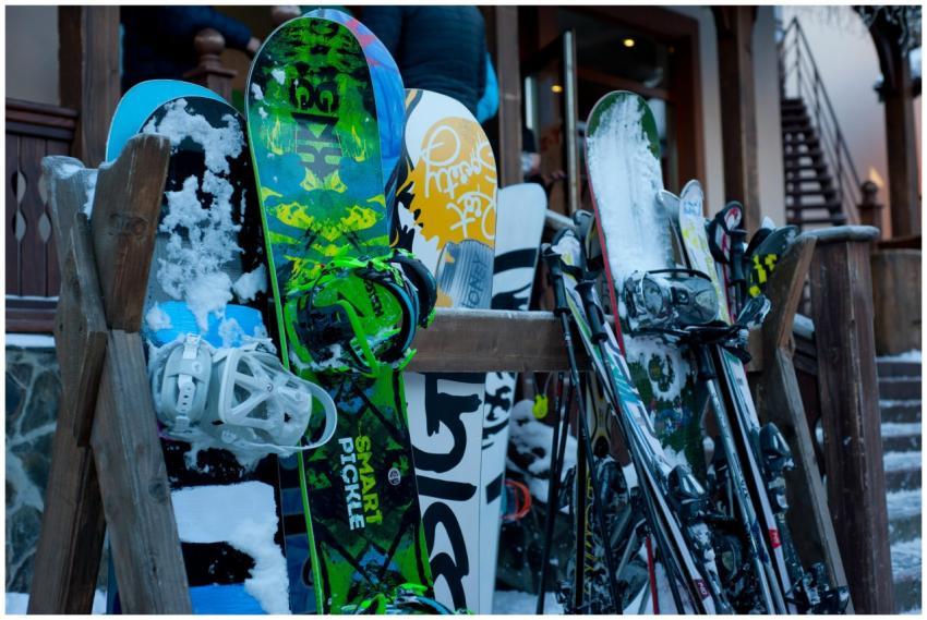 Snowboards and skis lined up outdoors at a winter