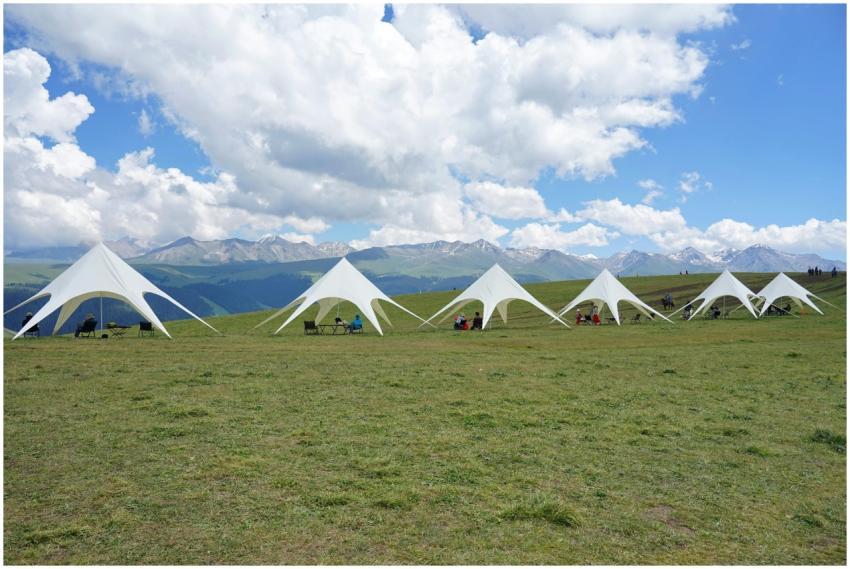 White tents on a picturesque grassy hill with moun