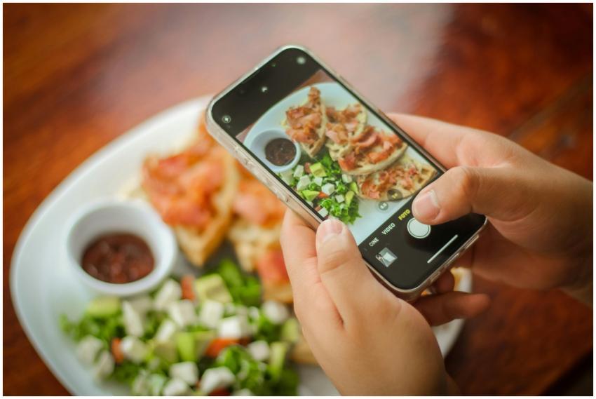 Close-up of hands photographing a brunch plate wit