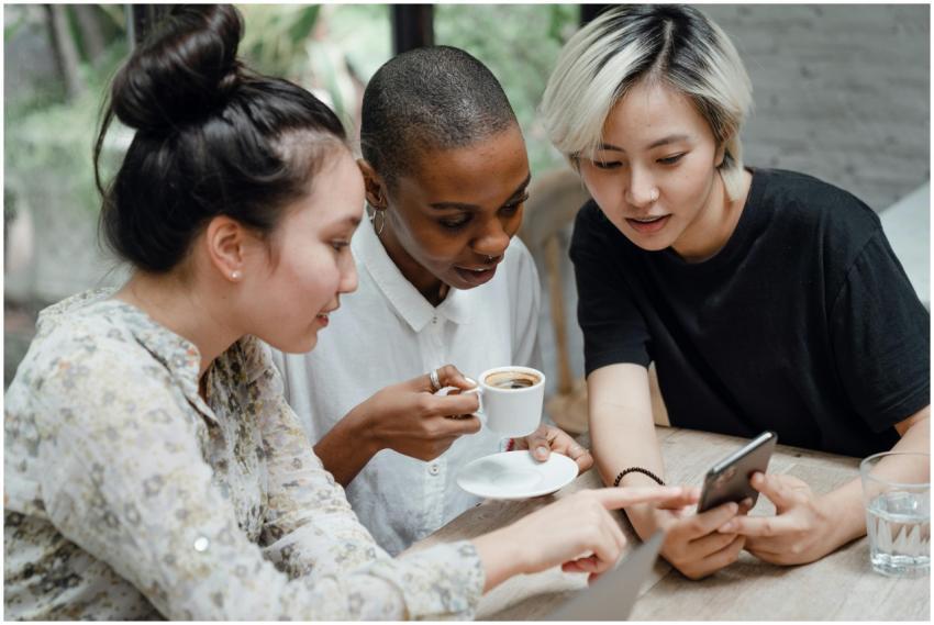 Three young women enjoying coffee and browsing soc