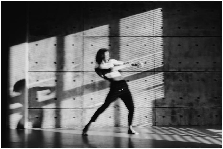 Grayscale image of a dancer in motion, casting a d