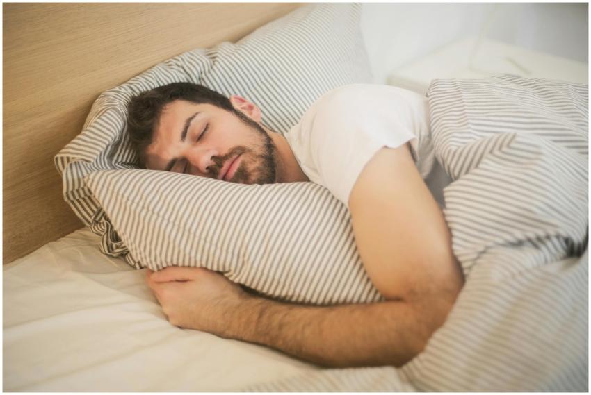 Man sleeping peacefully on striped bedding, embrac
