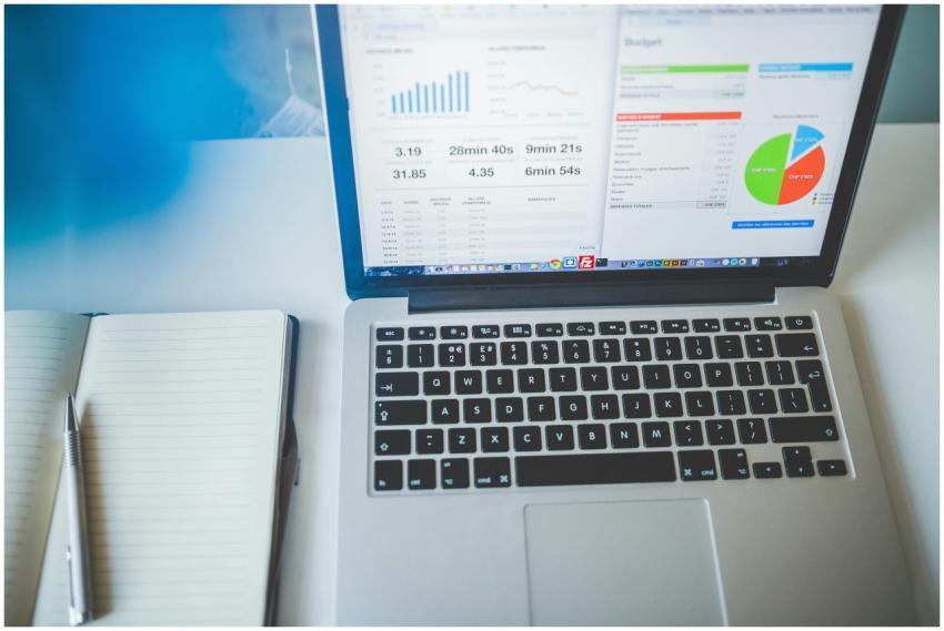 Laptop displaying charts and graphs next to a note