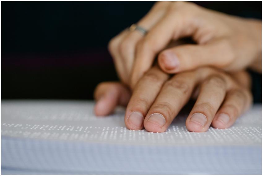 A detailed shot of hands touching a Braille book,