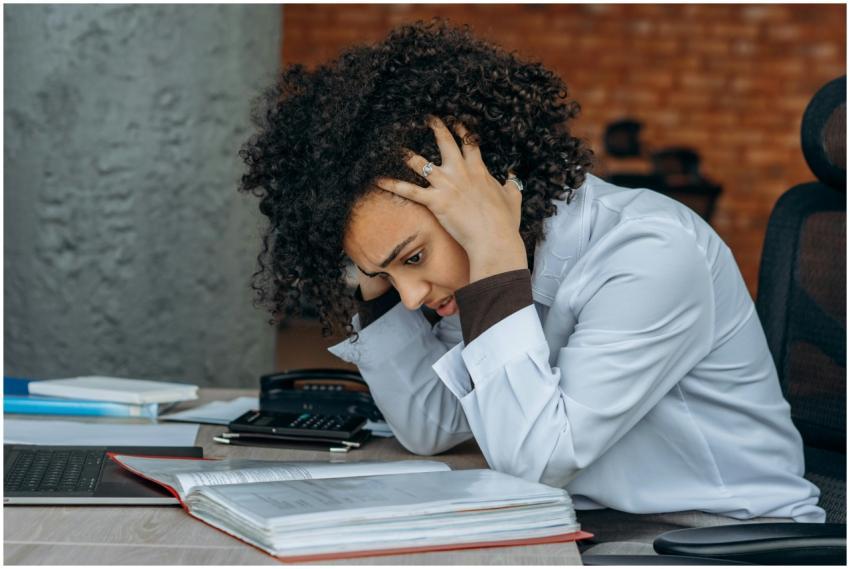 Woman sitting at desk appearing stressed while rev