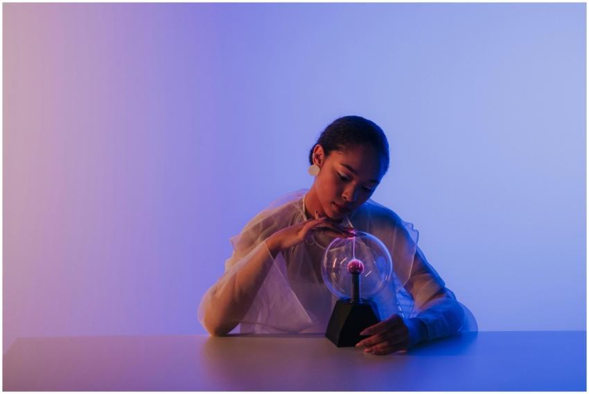 A woman touches a plasma ball, creating electric a