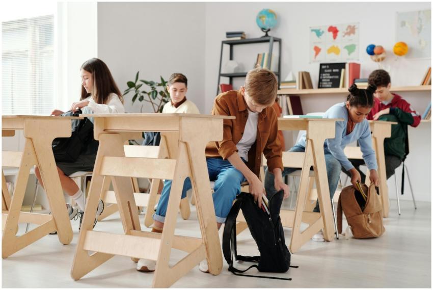 Teen students organizing backpacks in a bright cla