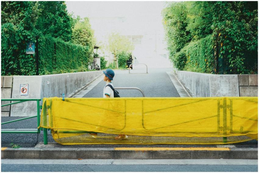 A person walking past a yellow construction barrie