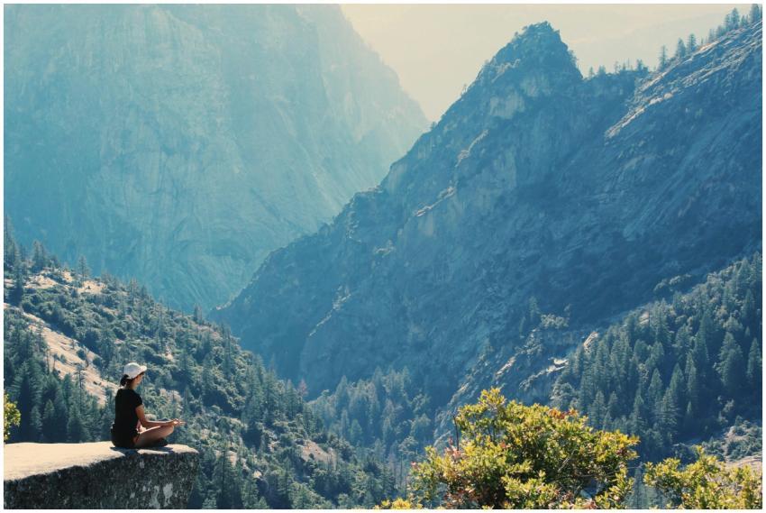 A woman practices meditation on a cliff edge, surr