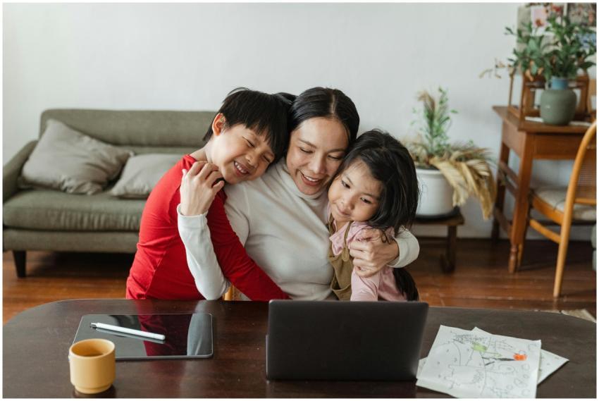 A mother embraces her children while working from