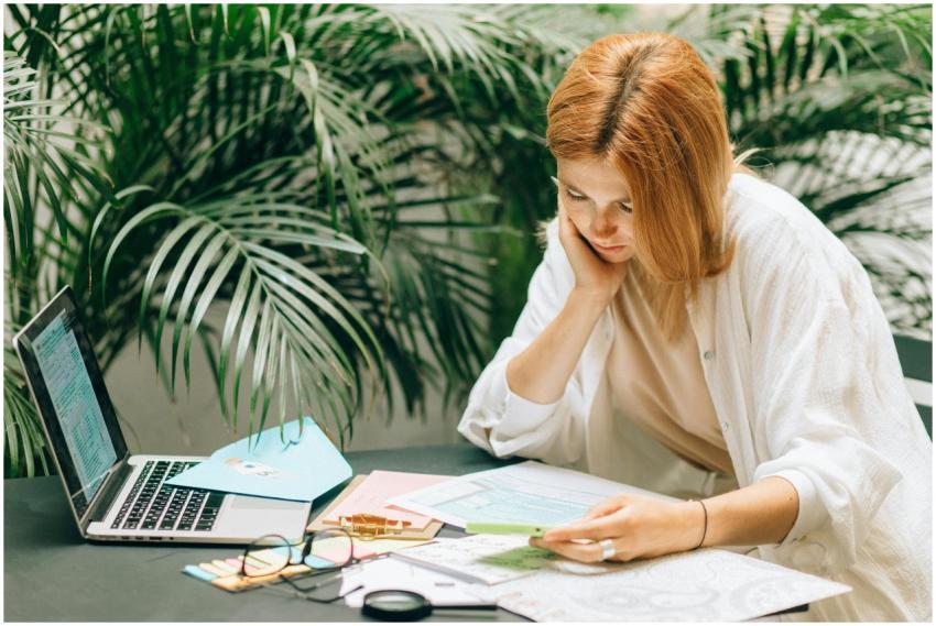 Woman in a thoughtful pose reviewing documents on