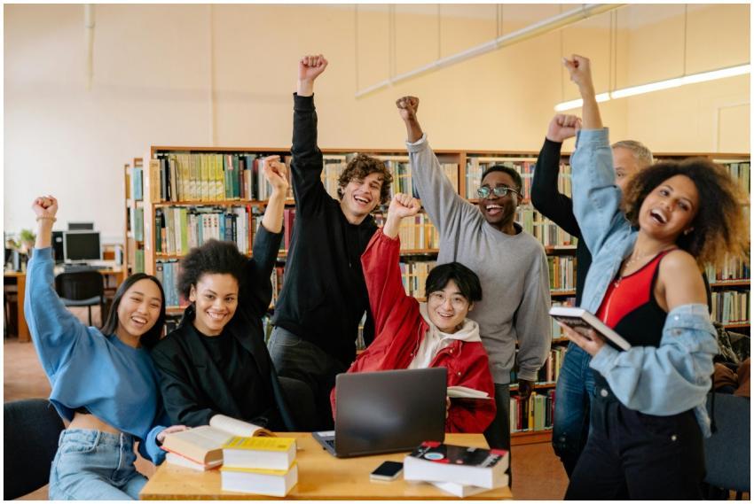 Happy diverse students in library raising hands, e