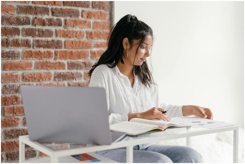 A woman in casual attire studies with a laptop and