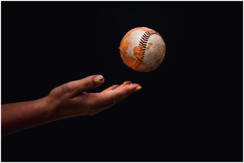 A hand tosses a paint-covered baseball, captured a