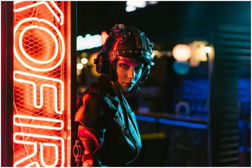 Woman in cyberpunk attire standing by neon sign in
