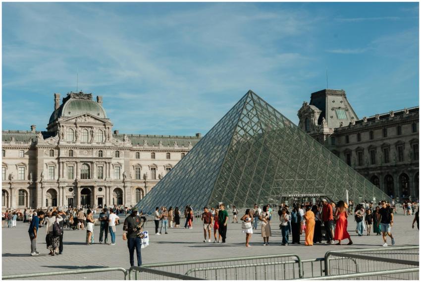 Crowds of tourists gather around the iconic Louvre