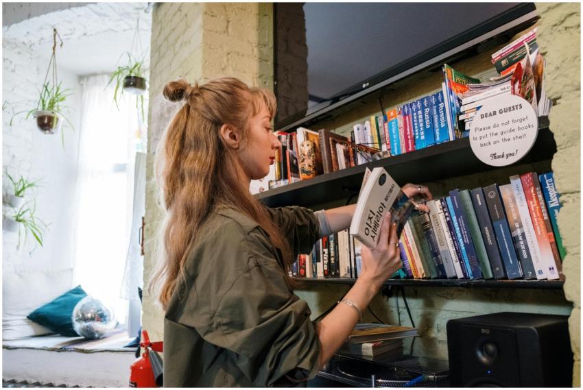 A woman browsing books on a shelf in a cozy indoor