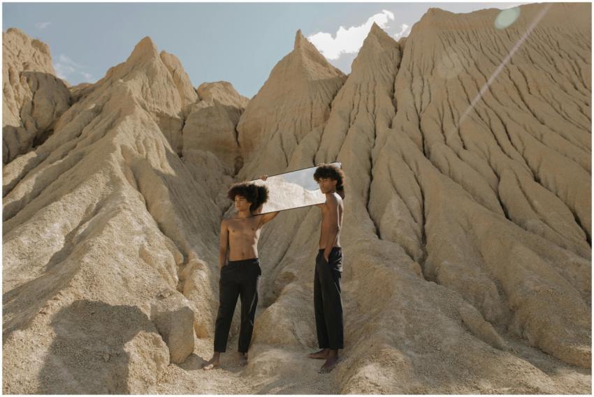 Two men with afro hair, holding a mirror, in a sur