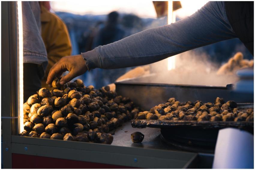 A street vendor's hand reaches over a pile of roas